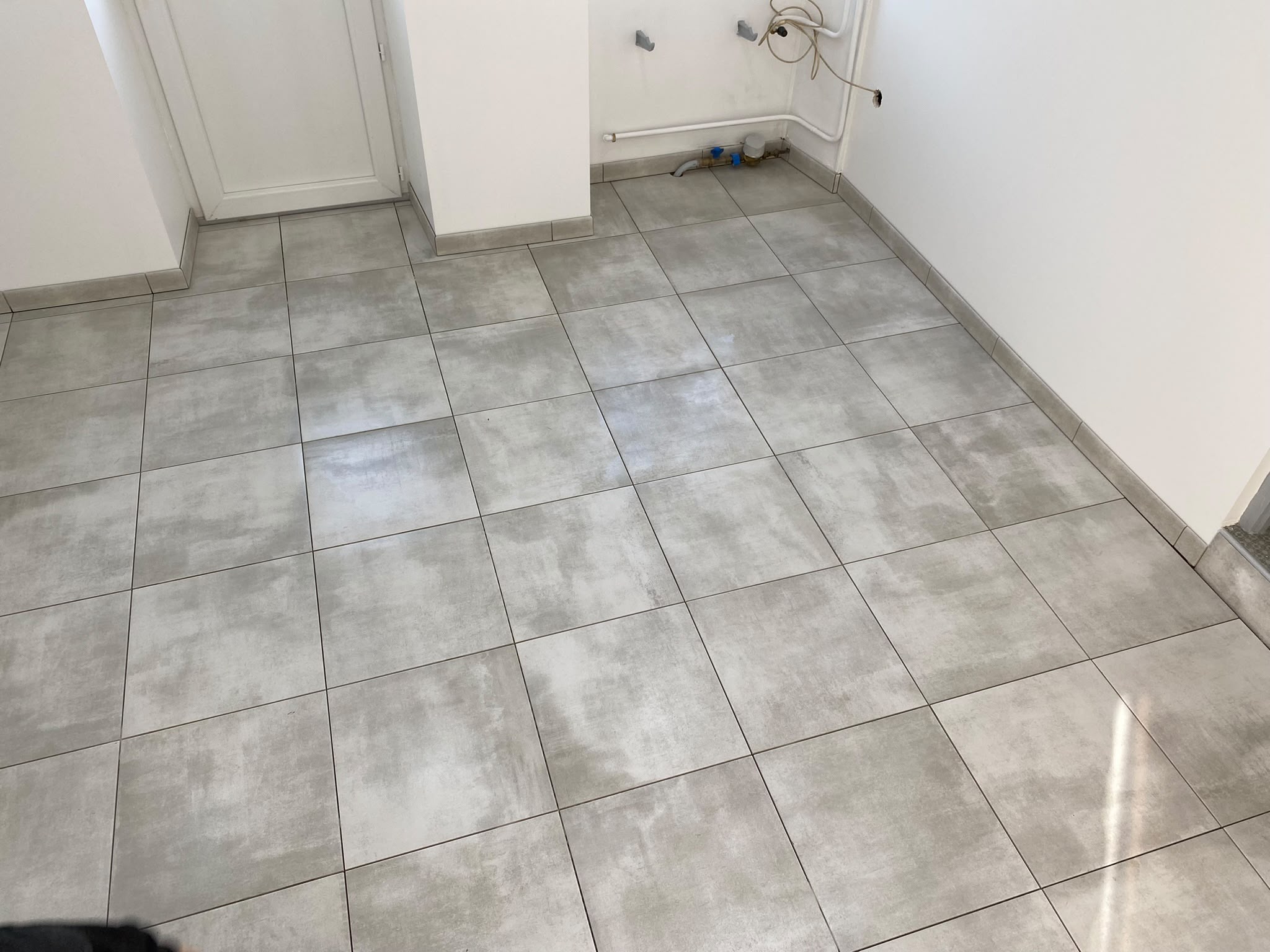 Carrelage gris posé avec joints réguliers et découpes nettes