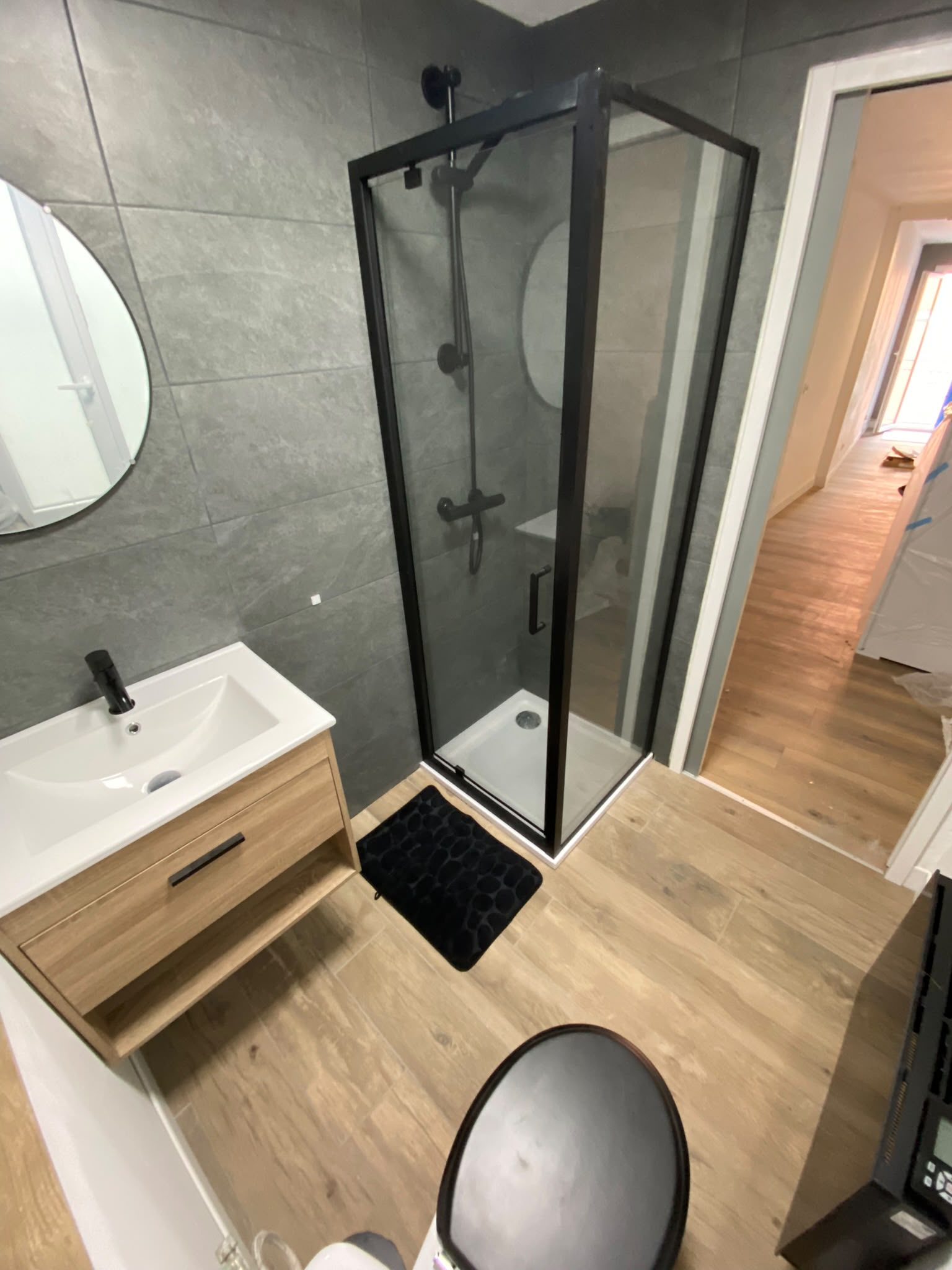 Salle de bain rénovée avec douche noire et meuble vasque bois — Alpes-Maritimes