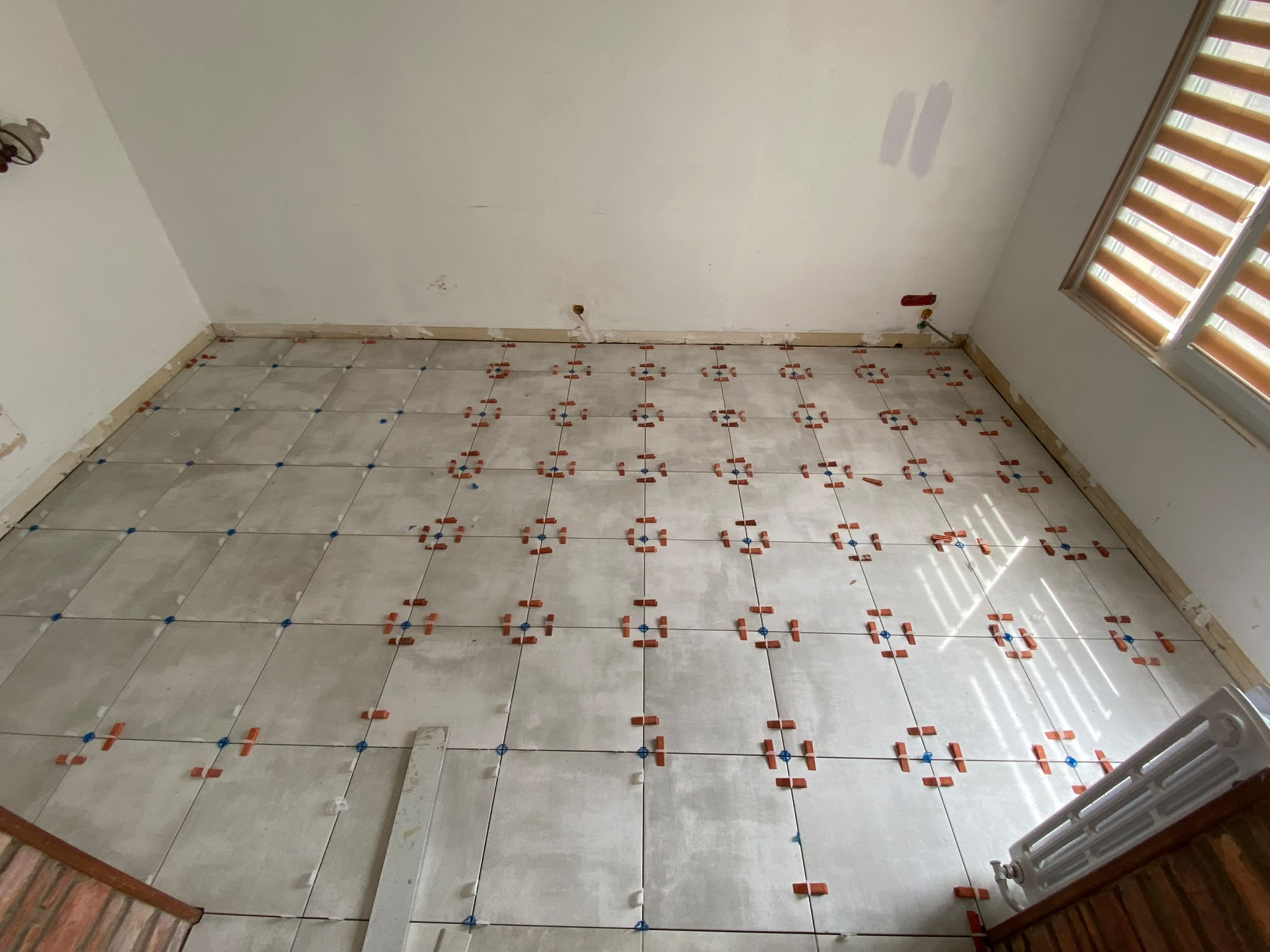 Pose de carrelage en cours avec système de croisillons auto-nivelants