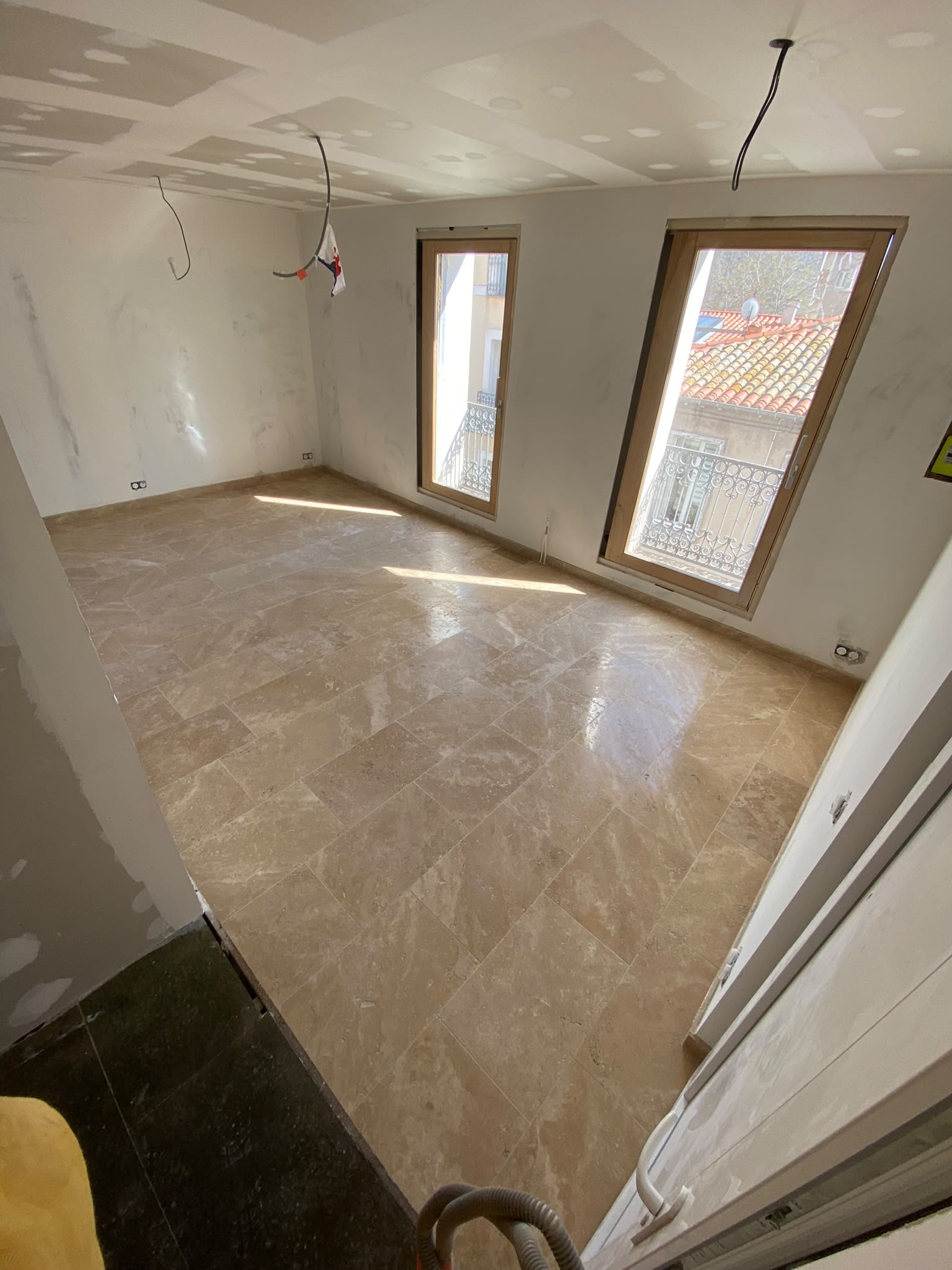 Pose de carrelage travertin grand format dans une pièce de vie