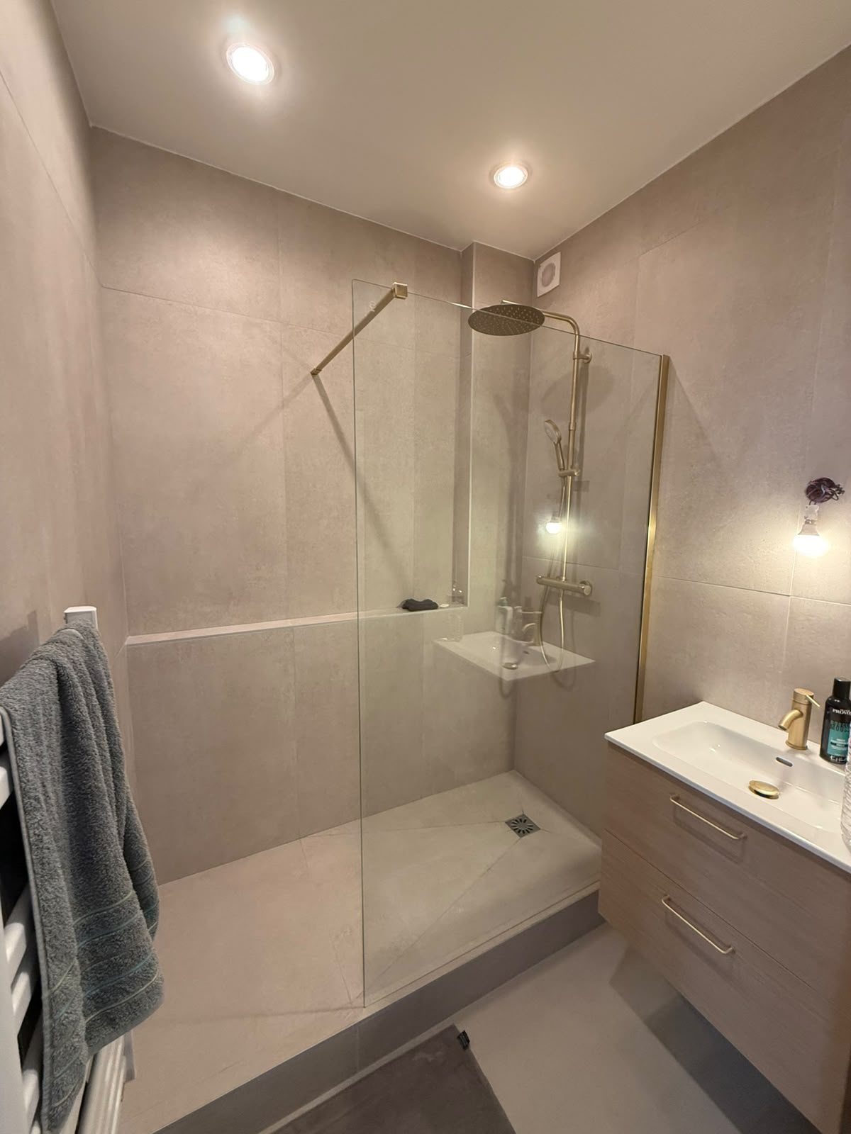 Salle de bain rénovée avec carrelage grand format gris et robinetterie dorée — Alpes-Maritimes