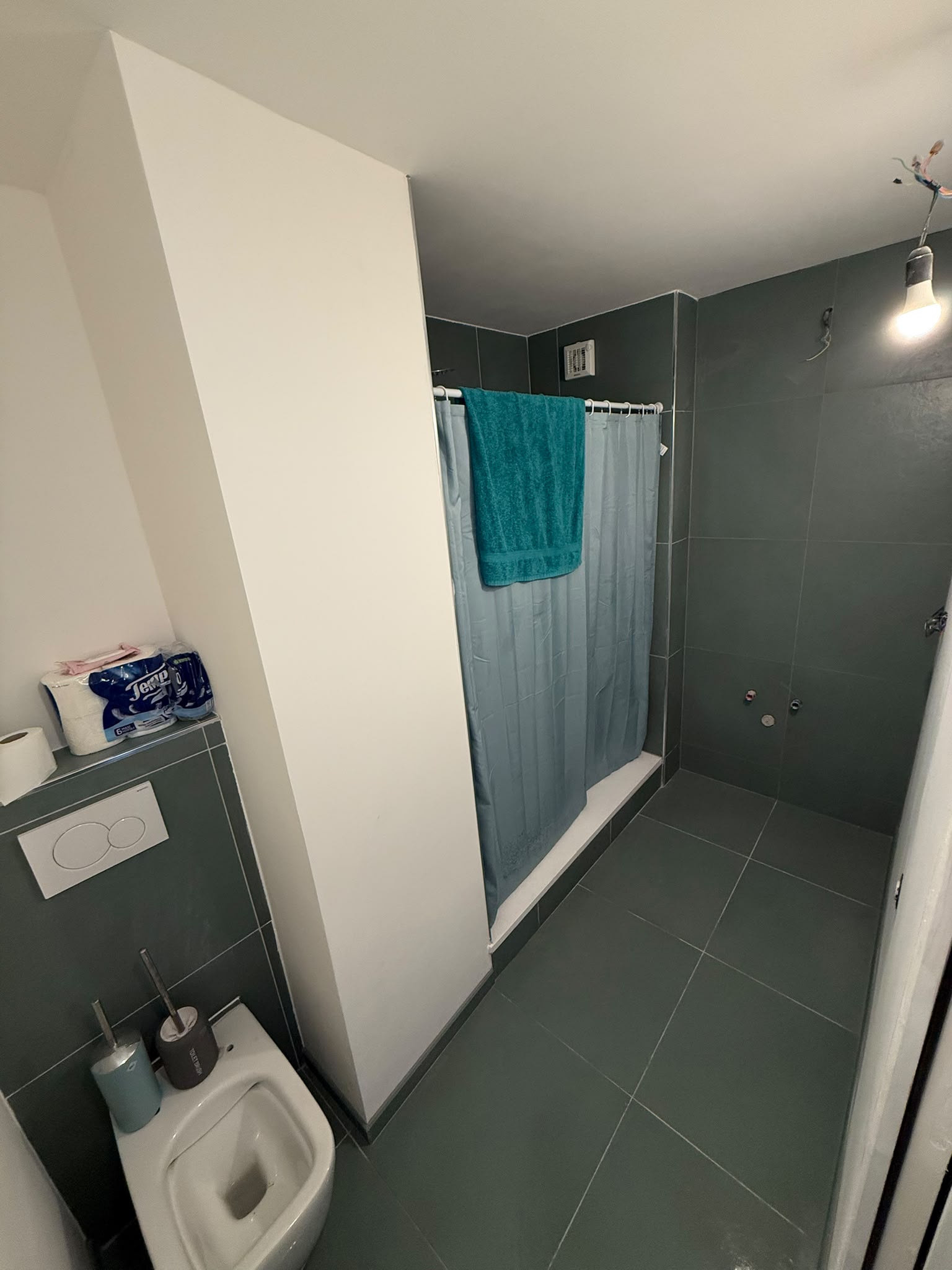 Salle de bain avec carrelage vert et cloison maçonnée